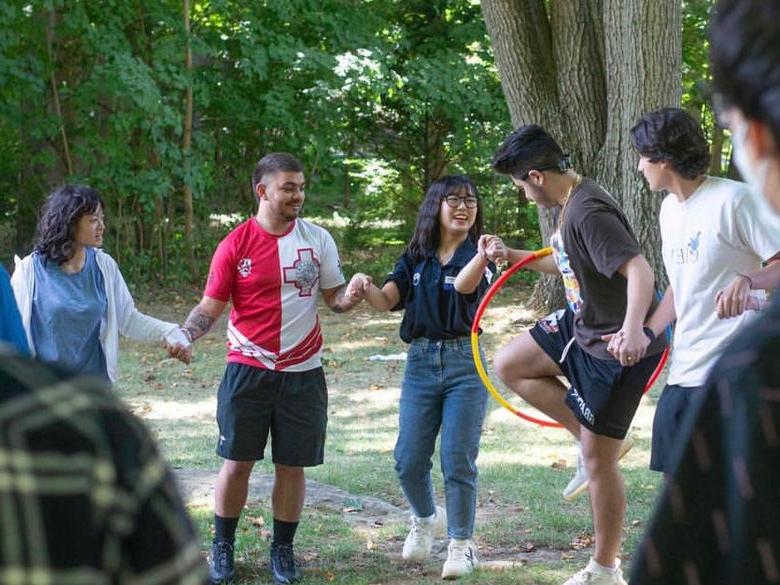 Student holding hands and passing hula hoop 